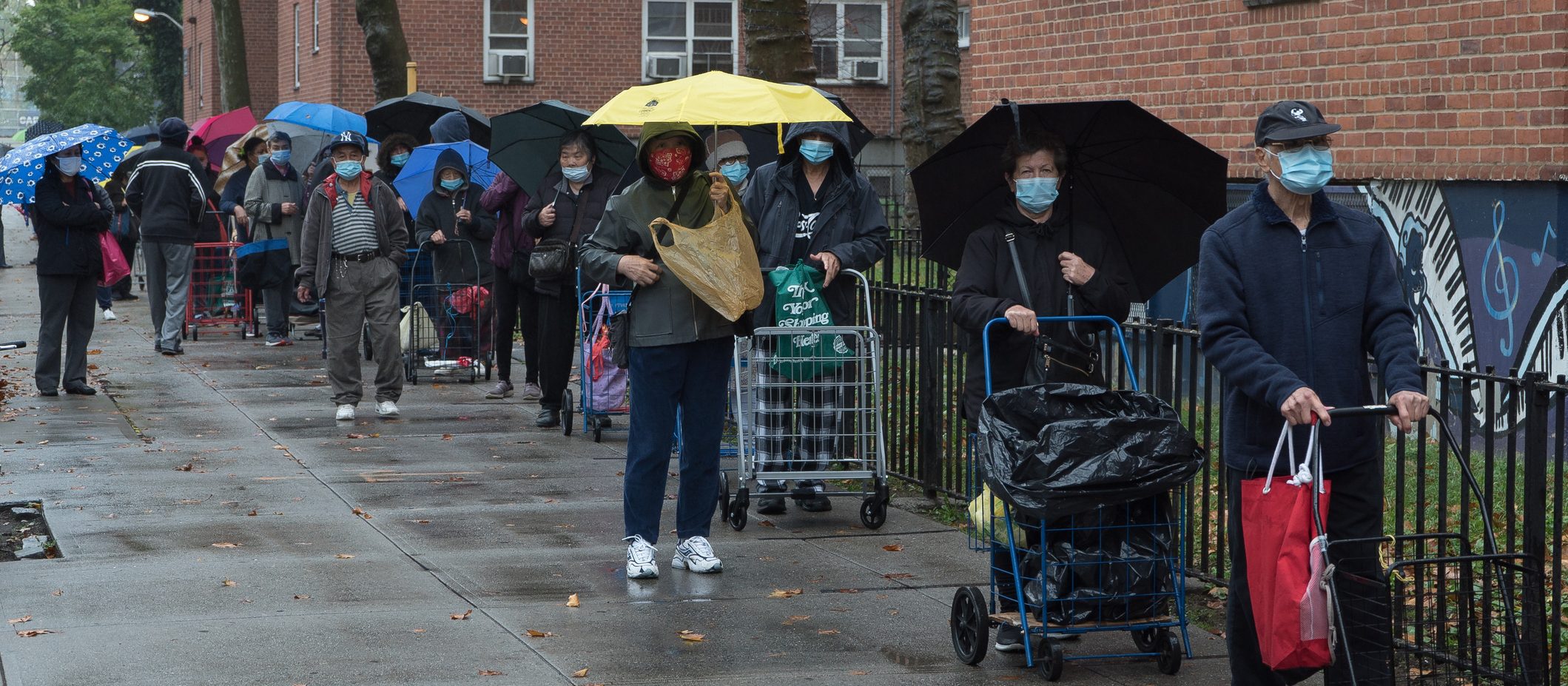 Queens, New York. October 28, 2020. A large crowd of people wait in line outside an outdoor food pantry in Woodside organized by "Sunnyside Community Services"