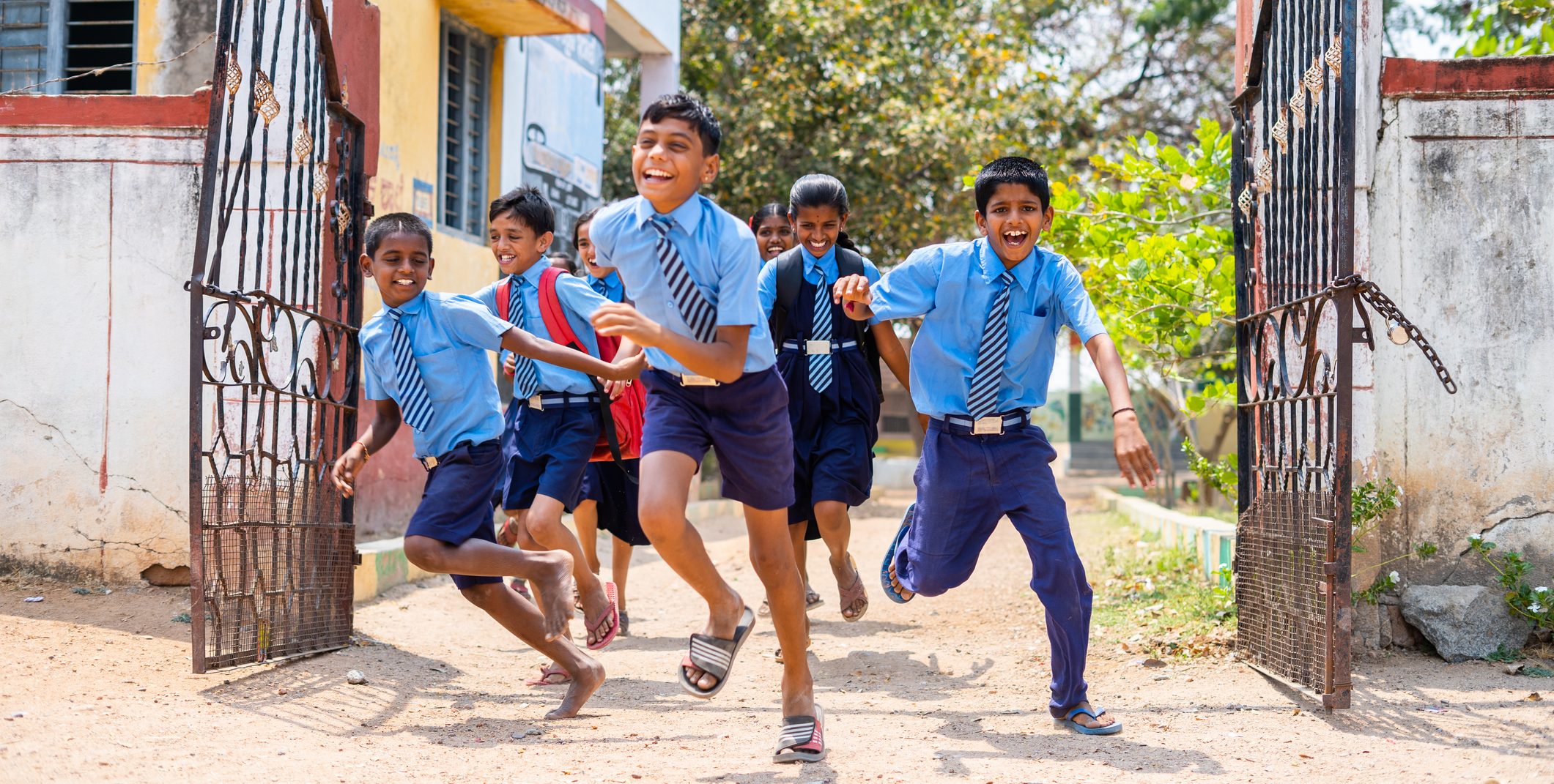 Children running out from school by opening gate after the bell - concept of education, freedom, happiness, enjoyment and childhood growth
